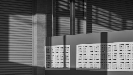 Light and shadow on roller shutter door surface of commercial buildings separated by a concrete fence, Street minimal architecture in black and white style