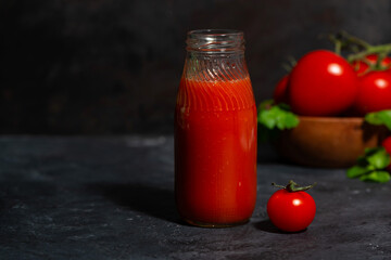 fresh tomato juice in a bottle on a dark background