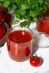 fresh tomato juice in glasses on a white background, greens and tomatoes, vertical
