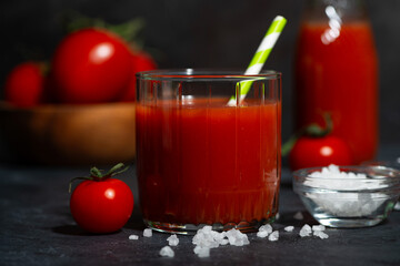 glass of fresh tomato juice with sea salt on a dark background, closeup