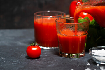 tomato juice is poured into a glass from a jug