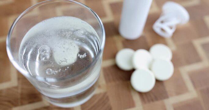 Person throws white tablet into glass of water. Water soluble vitamins concept
