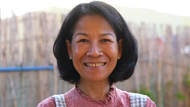 Happy senior asian woman smiling on camera outdoor - Thai ethnic person
