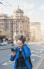 Beautiful puzzled tourist woman with mobile phone and backpack get lost near road in the Belgrade city, Serbia
