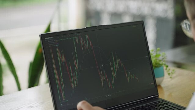 Market analyst reviews financial charts on laptop, analyzing trends for effective investments. Pro trader engages in day trading, examines stock data in modern office. Business strategy planning.