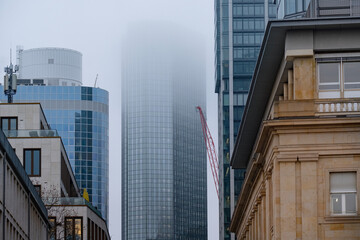 skyscrapers buildings disappear into the mist, creating mysterious and atmospheric urban landscape with blurred outlines and obscured details, Weather Conditions, German Engineering