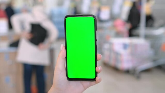 Use green screen for copy space closeup. Chroma key mock-up on smartphone in hand. Woman holds mobile phone and swipes photos or pictures left indoors of cozy home 4K