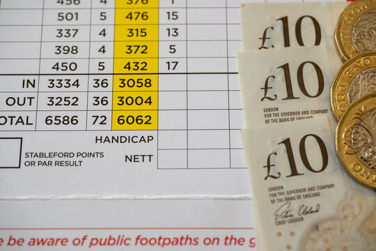 Close-up photograph of a Golf Course scorecard with cash in the form of ten pound notes and pound coins lying on the top of the score card.