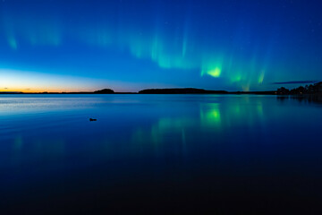 Northern light dancing over calm lake in north of Sweden.Farnebofjarden national park. - 774155257