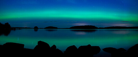 Northern light dancing over calm lake in north of Sweden.Farnebofjarden national park. - 774155266