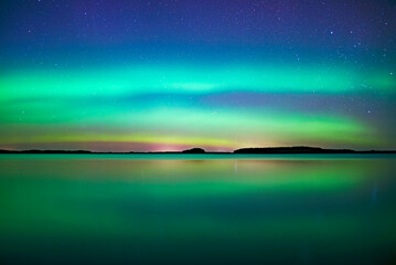 Northern light dancing over calm lake in north of Sweden.Farnebofjarden national park. - 774155496