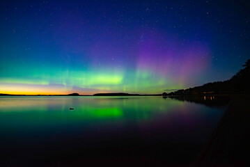 Northern light dancing over calm lake in north of Sweden.Farnebofjarden national park. - 774155641