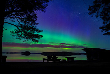 Northern light dancing over calm lake in north of Sweden.Farnebofjarden national park. - 774155697