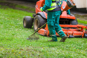 Lawn service workers mowing the green grass - obrazy, fototapety, plakaty