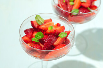 Strawberry healthy dessert with lemon sauce, honey and mint leaves in crystal vintage glasses, sunlight, mint background. Healthy summer, spring recipes, natural vitamins, summer vibes, close up - 774163851