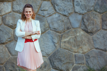 happy modern woman in pink dress and white jacket in city - 774166401