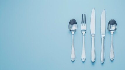 A minimalist arrangement of silverware on a pristine solid color tabletop - obrazy, fototapety, plakaty
