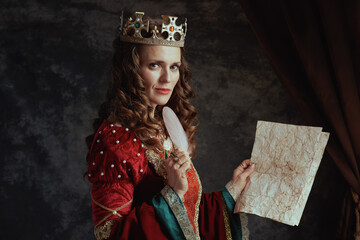pensive medieval queen in red dress with parchment and crown