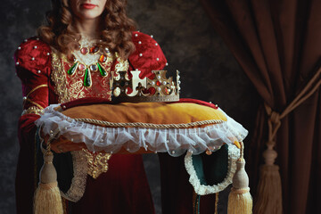 Closeup on medieval queen in red dress with crown on pillow