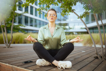 business woman in green blouse and eyeglasses meditating - 774166872