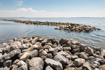 Fototapeta na wymiar Large boulders forming wave breakers in the Grevelingen lake to protect the little beachnear Battenoord at Goeree-Overflakkee in The Netherlands from the waves.
