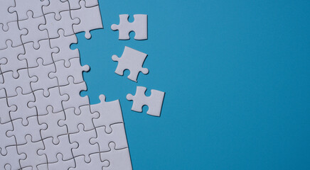 Unfinished white jigsaw puzzle on blue background with copy space. Business strategy teamwork and problem solving concept.