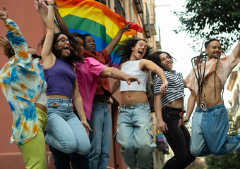 Low angle view of a large group of multuethnic gay people excited with rainbow flag in Madrid city chueca street