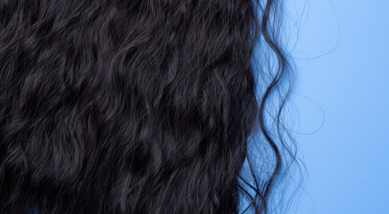 Close up of the texture of the shiny black human curly hair on the blue background