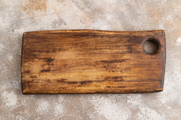 Empty rectangular wooden cutting board on brown concrete. Top view