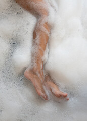 Woman legs in bath foam. Top view. Enjoying and relaxation - 774169419