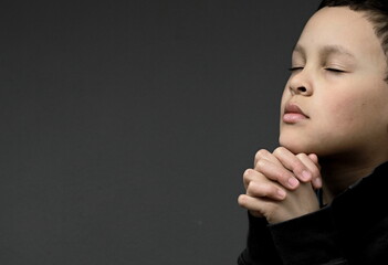 boy praying to God with hands together with people stock photo	