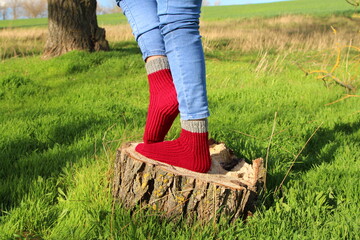 A person wearing socks and standing on a stump in a grassy area