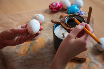 Woman hand painting easter egg with wax from candle. Traditional holiday habit, lifestyle background