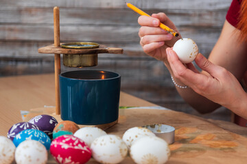 Woman hand painting easter egg with wax from candle. Traditional holiday habit, lifestyle background