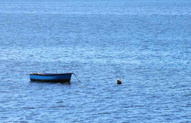 A small blue fishing boat close to the coast. Large copyspace.