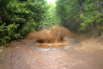 photo of suv racing thru a mud puddle splashing mud on a backcountry road in idaho
