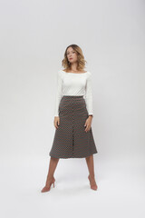 Serie of studio photos of female model wearing viscose fitted white shirt and patterned midi skirt...