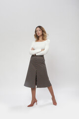Serie of studio photos of female model wearing viscose fitted white shirt and patterned midi skirt with slit