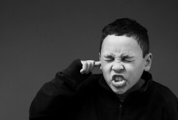 boy suffering from deafness and hearing loss on grey background stock photo