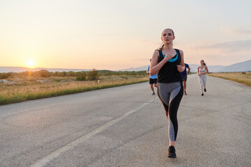 A diverse group of runners trains together at sunset. - obrazy, fototapety, plakaty