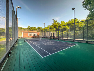 Summertime scene of elevated sport courts with nets in a public park setting. Courts are used for paddle tennis or pickleball play. Floor surface is green and blue with white boundary lines. - obrazy, fototapety, plakaty