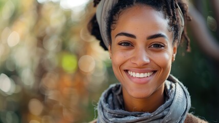 A smiling woman with a headscarf outdoors blurry foliage background - obrazy, fototapety, plakaty