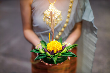 Thai woman wearing thai traditional dress holding krathong made form lotus flower and banana leaf...