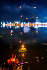 krathong with candle ight floating on blue surface water in river at night, Loy Krathong festival