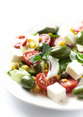 Healthy Salad with Feta Cheese, Green Olives, Baby Spinach, Cucumber, Cherry Tomatoes and Capers. Bright background. Close up.	