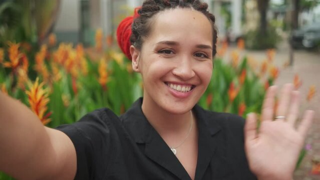 Young caucasian pretty woman with red dreadlocks making selfie with happy smile on background exotic plants