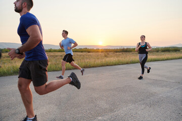 A diverse group of runners trains together at sunset.