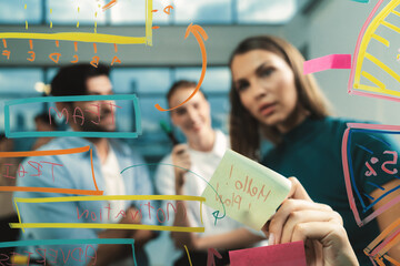 Skilled project manager pointing at glass wall while coworker thinking about plan. Diverse business team working together, brainstorming marketing idea or business plan. Creative start up. Tracery.