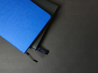 Two closed notepads on a dark background