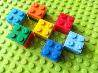 Plastic Colorful Construction and Building Blocks on Green Baseplate